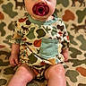 baby, infant, child, sitting, portrait, face, wide_eyes, pacifier, bow_headband, camouflage, outfit, blanket, patterned, green, colorful, indoors, adorable, toes, barefoot, photography
