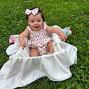 Aviana is registered to the contest to win money with this photo: baby, blanket, child, clothing, cute, face, grass, greenery, happy, headband, infant, nature, outdoor, person, playful, portrait, sitting, smiling, summer, young