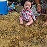 Aviana is registered to the contest to win money with this photo: baby, child, sand, beach, floral_swimsuit, wild_hair, adult_hand, cooler, toys, outdoor, nature, curious_expression, sitting, barefoot, sunny, relaxed, summer, playtime, family, vacation