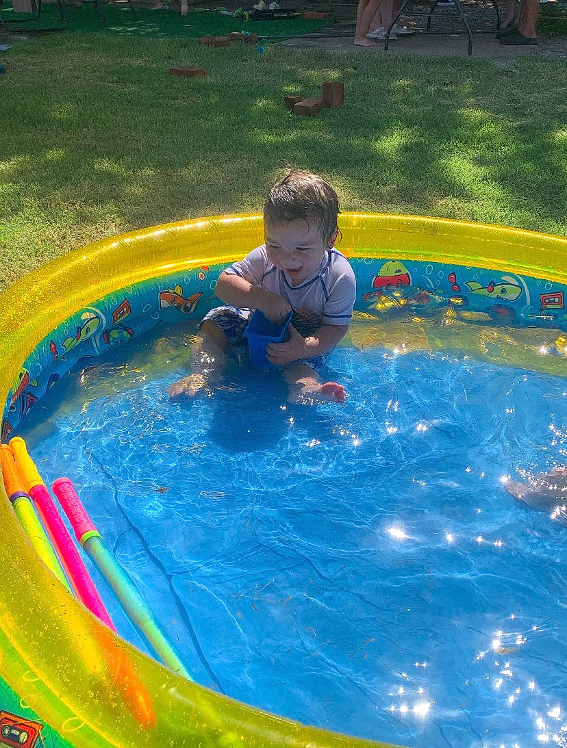 Forrest is registered to the contest to win money with this photo: baby, bathing, child, circle, composite_material, electric_blue, fluid, fun, grass, leisure, nonbuilding_structure, outdoor_recreation, person, play, recreation, toddler, water