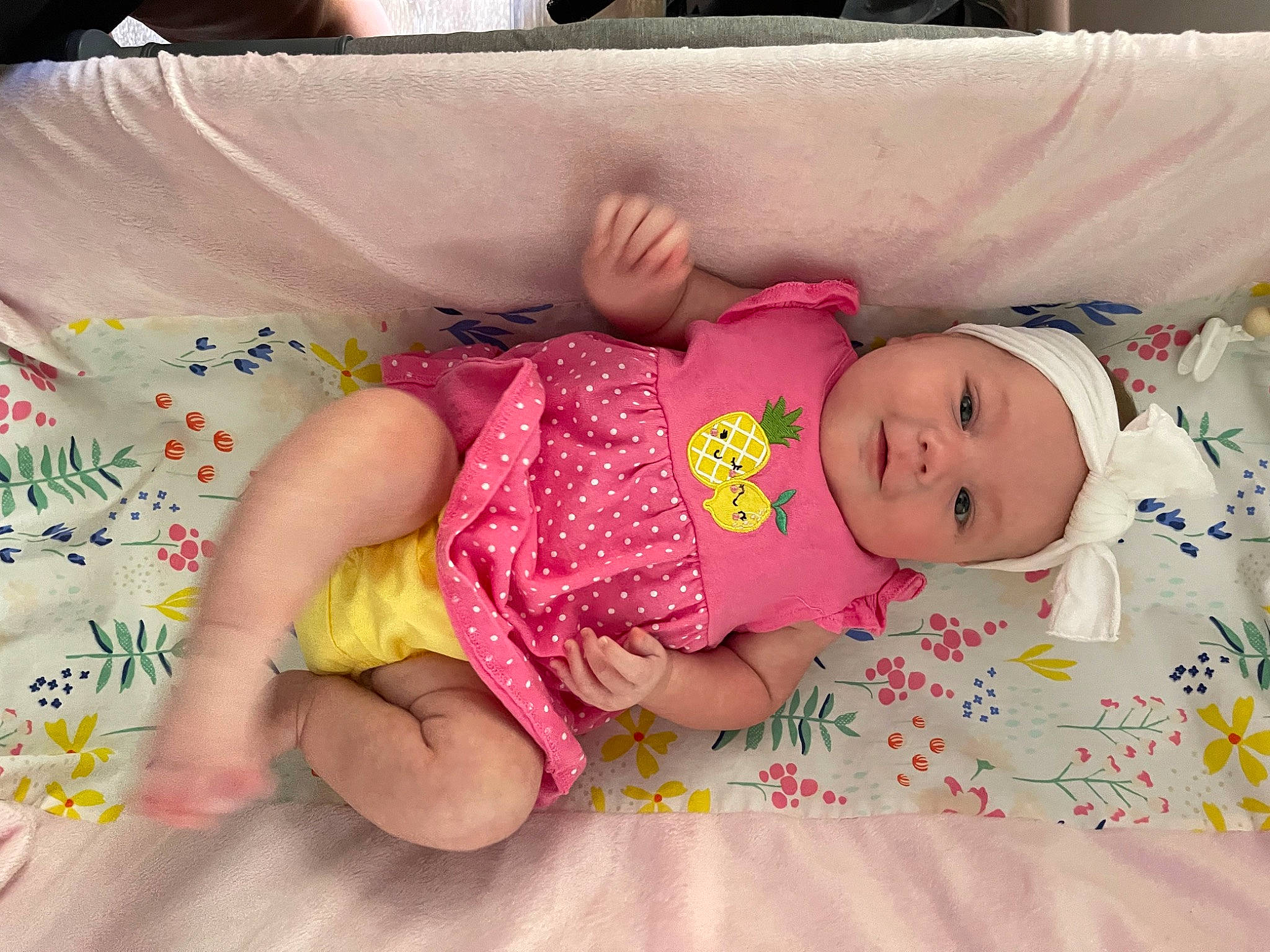 Dani is registered to the contest to win money with this photo: arm, baby, baby_toddler_clothing, bed, cheek, comfort, eye, facial_expression, finger, hand, happy, headwear, iris, linens, pattern, person, pink, skin, sleeve, textile