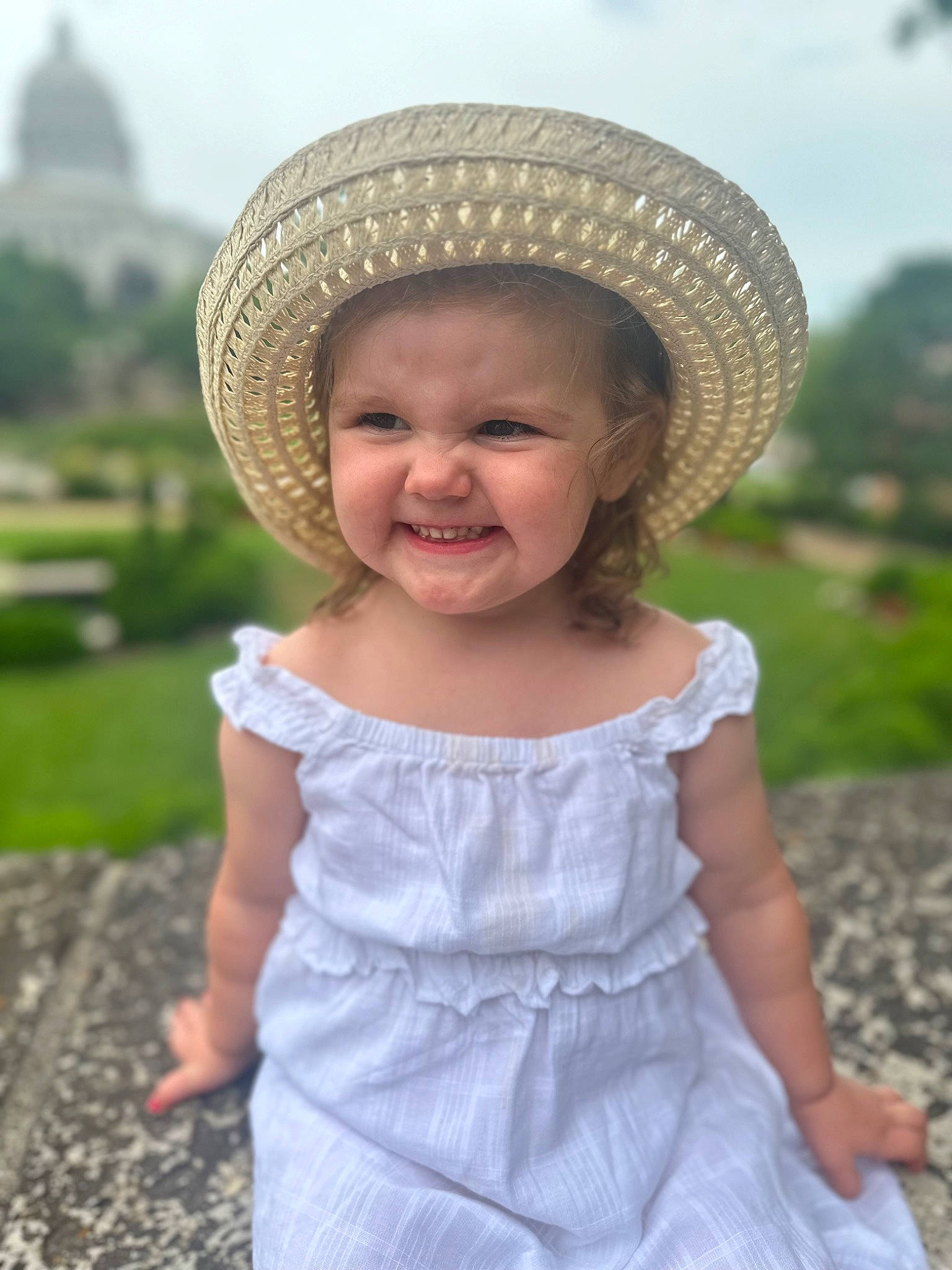 Laila is registered to the contest to win money with this photo: baby_toddler_clothing, dress, face, facial_expression, fun, grass, happy, hat, headgear, joy, people_in_nature, person, photograph, plant, skin, sky, smile, summer, sun_hat, sunlight