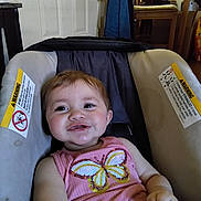 Ellie is registered to the contest to win money with this photo: baby, child, car_seat, pink_clothing, butterfly, smiling, indoor, door, chair, household, seat, infant, person, cute, happy, young_child, casual, comfort, small_child, portrait
