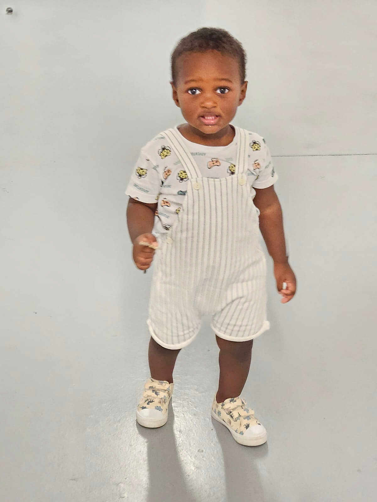 Hakeem a rejoint le concours — aidez-le/la à gagner de superbes lots ! baby, child, clothing, curious, cute, expression, fashion, floor, footwear, indoor, kid, overalls, person, portrait, shirt, shoes, sneakers, standing, toddler, young_child