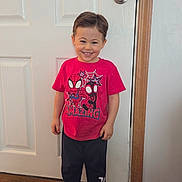 Michael is registered to the contest to win money with this photo: barefoot, casual_clothing, child, cute, door, graphic_tee, happy, home, indoors, navy_pants, person, red_tshirt, short_hair, smiling, spiderman, standing, toddler, white_door, wood_floor, young