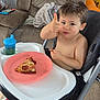 blanket, carpet, child, couch, cup, eating, furniture, happy, high_chair, indoor, living_room, pepperoni_pizza, person, pikachu, pizza, plate, plush_toy, sippy_cup, thumbs_up, toddler