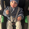 Adan participe au concours pour gagner de l'argent avec cette photo : baby, child, car_seat, blue_hat, knit_sweater, white_pants, socks, smiley_faces, indoor, seat_belt, cute, infant, portrait, cozy, warm_clothing, baby_clothing, black_car_seat, green_accent, floor, curious_expression
