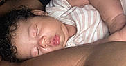 Mai is registered to the contest to win money with this photo: baby, sleeping, curly_hair, striped_clothing, arm, close_up, peaceful, child, infant, skin, face, resting, cute, adorable, portrait, person, soft_light, indoors, toddler, comfort