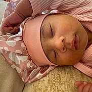 Mai is registered to the contest to win money with this photo: baby, sleeping, pink_clothing, hat, infant, peaceful, soft_fabric, closeup, child, resting, cute, indoors, portrait, cozy, skin, headwear, peace, relaxation, small_hand, face