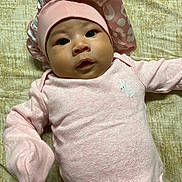 Mai is registered to the contest to win money with this photo: baby, bonnet, bunny_emblem, child, cute, expression, face, headwear, indoors, infant, lying_down, newborn, person, pink_clothing, portrait, resting, skin, sleepwear, soft_texture, young