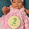 baby, infant, pink_dress, headband, smiling, cute, portrait, milestone, sign, months_old, frilly_clothing, cushion, indoor, child, adorable, young, celebration, happy, person, two_months
