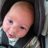 baby, infant, car_seat, headrest, smile, face, child, seatbelt, safety, clothing, closeup, cute, skin, eyes, mouth, tongue, hair, expression, indoors, person