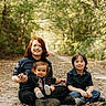 children, siblings, baby, toddler, portrait, smiling, outdoor, forest, woodland, nature, family, sitting, path, trees, sunlight, leaves, casual_clothing, black_shirts, blue_jeans, group_photo