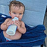 Theodore is registered to the contest to win money with this photo: baby, bottle, milk, blue_eyes, towel, wet_hair, lounge_chair, skin, diaper, outdoor, person, child, feeding, infant, cute, relaxing, summer, drink, texture, closeup