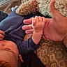 adult_hand, baby, bed, blanket, blue_outfit, child, closeup, clothing, comfort, cuddle, grip, hand, person, plush_toy, rest, skin, sleeping, soft_texture, toddler, warm