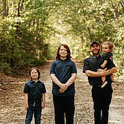 Theodore is registered to the contest to win money with this photo: family, children, toddler, parent, father, outdoor, forest, woodland, nature, trail, path, portrait, group_photo, standing, smiling, casual_clothing, cap, trees, daylight, family_outing
