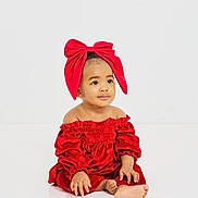 Azaiya Green is registered to the contest to win money with this photo: baby, child, red_dress, red_bow, sitting, barefoot, portrait, cute, adorable, indoor, white_background, fashion, young_child, infant, smiling, studio_photo, hands, feet, headwear, calm