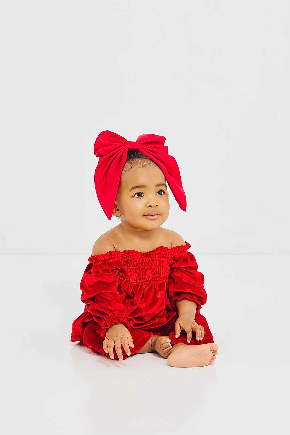 Azaiya Green is registered to the contest to win money with this photo: baby, child, red_dress, red_bow, sitting, barefoot, portrait, cute, adorable, indoor, white_background, fashion, young_child, infant, smiling, studio_photo, hands, feet, headwear, calm