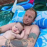 baby, infant, sleeping, father, parent, pool, swimming_pool, floatie, inflatable_swan, outdoor, water, family, bonding, tattoos, relaxing, summer, sunlight, portrait, poolside, peaceful