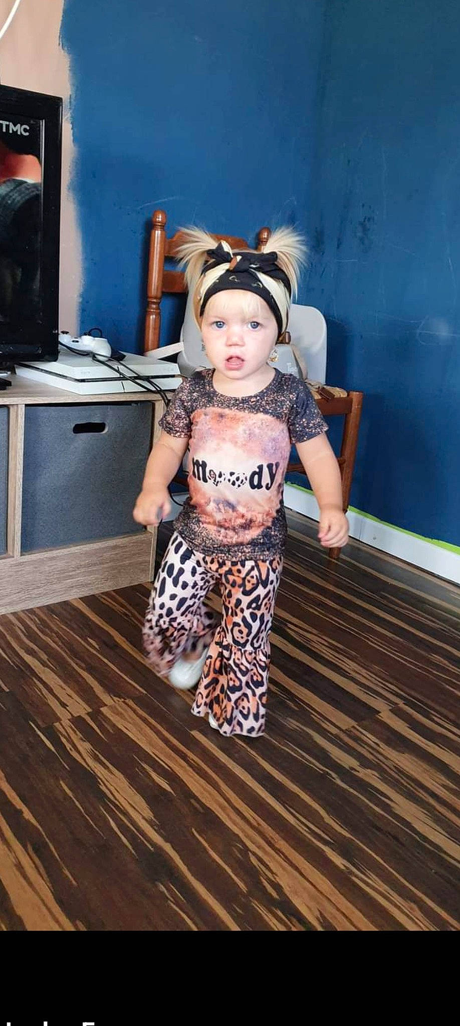 Lina participe au concours pour gagner de l'argent avec cette photo : baby, baby_toddler_clothing, child, dress, face, fashion_design, fawn, floor, flooring, fun, happy, hardwood, headwear, human_leg, person, personal_protective_equipment, room, standing, t_shirt, television