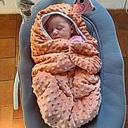 Lilou participe au concours pour gagner de l'argent avec cette photo : baby, blanket, sleeping, infant, baby_rocker, toy, soft_texture, peaceful, indoor, floor, tiled_floor, child, wrapped, cozy, pink, gray, plush, head, resting, cute