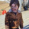 Tatum is registered to the contest to win money with this photo: child, mud, dirty, outdoor, jacket, smiling, face, dirt, play, happy, person, young, messy, clothing, nature, wooden_deck, casual, fun, adventure, daylight