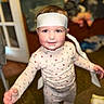 toddler, child, pajamas, headband, indoor, smiling, reaching, face, person, young_child, curious, happy, fabric, blurry_background, home, clothing, cute, portrait, baby, floor