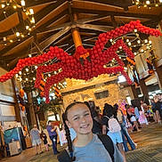 Jaime joined the competition — help win amazing prizes! child, girl, braid, smile, backpack, balloon_sculpture, spider_balloon, indoor, event, people, carpet, wood_floor, ceiling_lights, decorations, festive, casual_clothing, crowd, holiday, celebration, architecture
