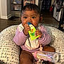 Kyomi is registered to the contest to win money with this photo: baby, infant, child, bottle, bib, cushion, indoor, floor, sock, clothing, hand, face, eyes, hair, toy, room, furniture, baby_bottle, holding, sitting