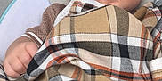 Reggie is registered to the contest to win money with this photo: baby, blanket, plaid, infant, child, face, blue_eyes, clothing, seat, comfort, indoor, portrait, cute, young, skin, expression, hand, head, soft, resting