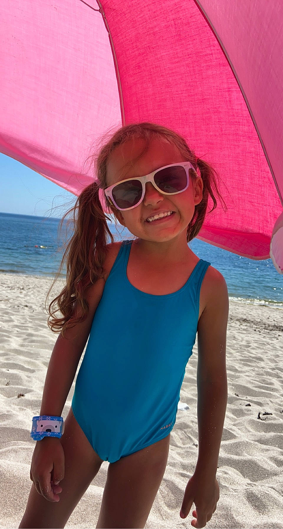 Léyna participe au concours pour gagner de l'argent avec cette photo : azure, clothing, eyewear, glasses, goggles, hair, hairstyle, happy, head, joy, leisure, one_piece_swimsuit, people_on_beach, person, pink, sky, smile, standing, sunglasses, swimwear