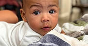 Legend is registered to the contest to win money with this photo: baby, blanket, child, closeup, couch, curious, cute, expression, eyes, face, furniture, hair, indoor, infant, lying_down, person, portrait, skin, soft_light, young