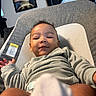 Legend is registered to the contest to win money with this photo: baby, infant, child, smile, face, cushion, baby_seat, clothing, long_sleeve, indoors, window, blinds, curtain, wall_art, poster, person, skin, head, hand, comfort