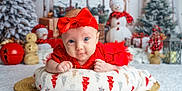 Soraya is registered to the contest to win money with this photo: baby, infant, red_bow, red_dress, blanket, snowman, christmas_tree, holiday_decorations, presents, festive, indoor, portrait, cute, smiling, winter, christmas, holiday, decor, soft_lighting, cozy