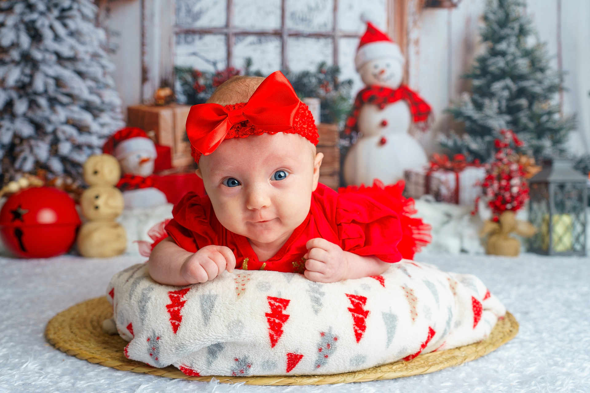 Soraya is registered to the contest to win money with this photo: baby, infant, red_bow, red_dress, blanket, snowman, christmas_tree, holiday_decorations, presents, festive, indoor, portrait, cute, smiling, winter, christmas, holiday, decor, soft_lighting, cozy
