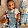 baby, child, infant, toddler, plush_toy, stuffed_animal, mickey_mouse, overalls, clothing, smiling, face, cute, soft_toys, bedroom, blanket, carpet, indoor, playtime, comfort, happy