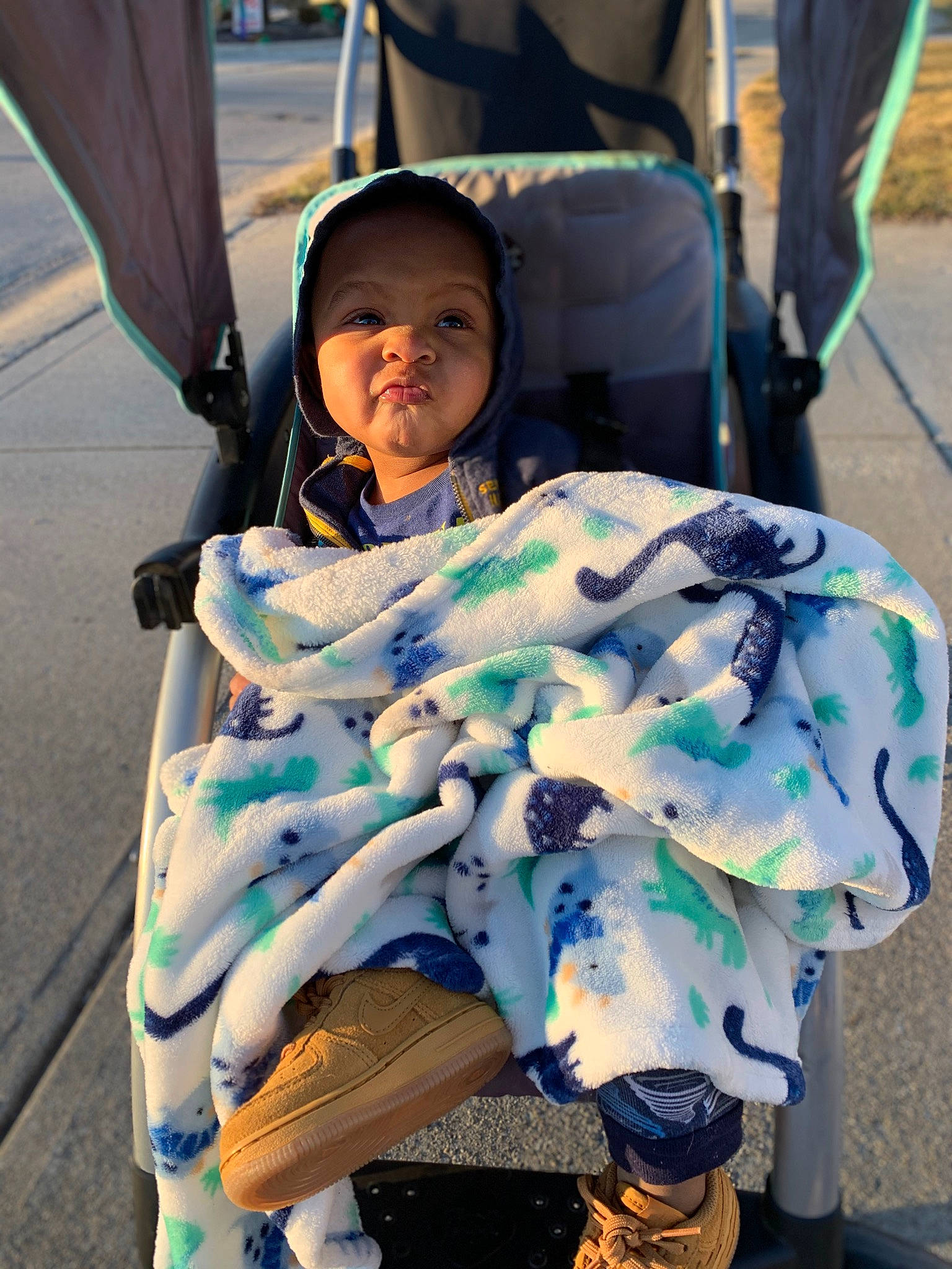 Kamari is registered to the contest to win money with this photo: auto_part, baby, baby_carriage, baby_products, child, electric_blue, event, eyewear, fun, motor_vehicle, person, photograph, public_event, recreation, road, sandal, shoe, sitting, street, toddler