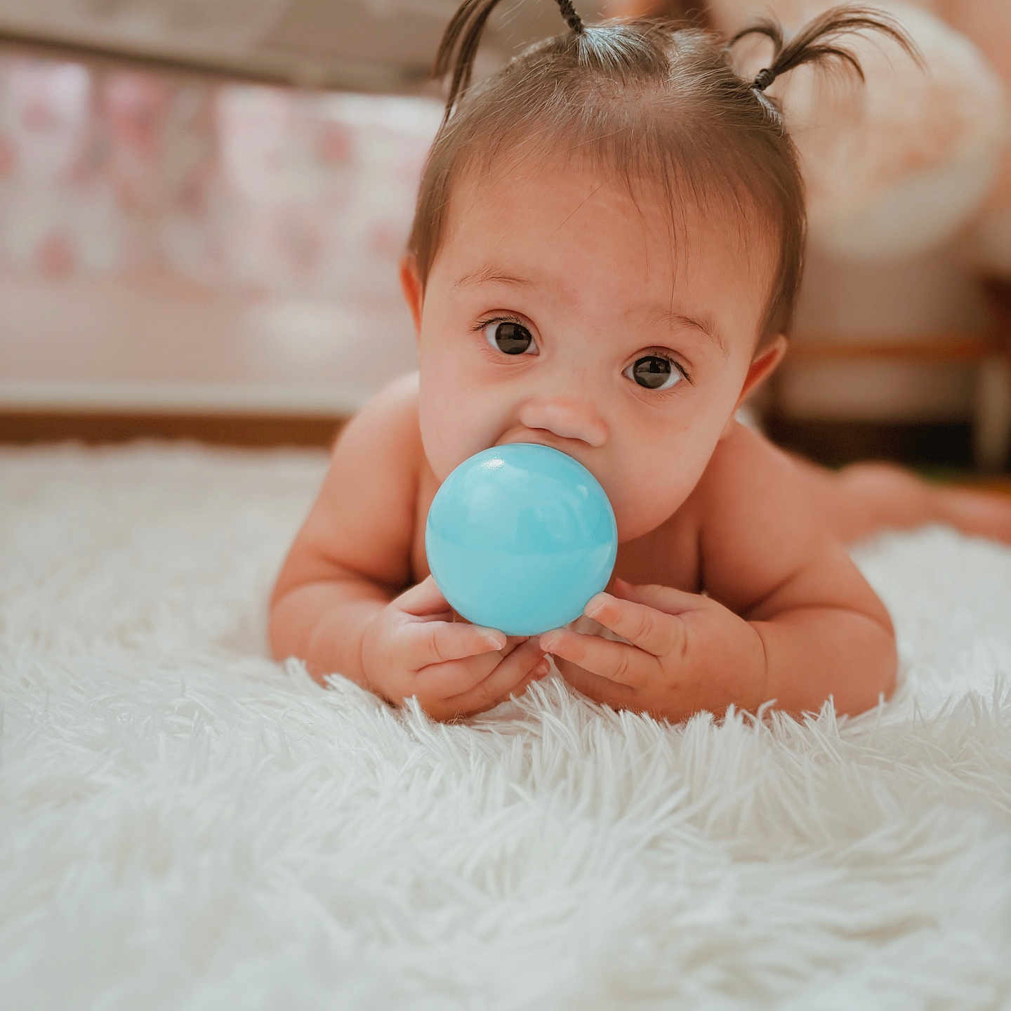 Velincia is registered to the contest to win money with this photo: baby, blue_ball, carpet, child, closeup, curious, cute, eyes, face, floor, hands, indoor, infant, lying_down, person, pigtails, skin, soft, toy, young_child