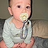 Nehemiah joined the competition — help win amazing prizes! baby, pacifier, onesie, dinosaur_print, bed, cross_legged, red_eye, infant, child, person, indoor, sleepwear, cute, face, hands, feet, skin, light, flash, expression