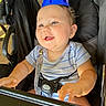 baby, child, party_hat, smiling, stroller, seatbelt, blue, striped_shirt, outdoor, sunlight, happy, infant, face, hands, person, cute, young_child, baby_clothes, seat, celebration