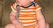Nehemiah joined the competition — help win amazing prizes! baby, child, closeup, couch, curious, cute, face, foot, furniture, hand, indoors, infant, onesie, pacifier, plump, portrait, sitting, skin, soft_texture, striped_clothing