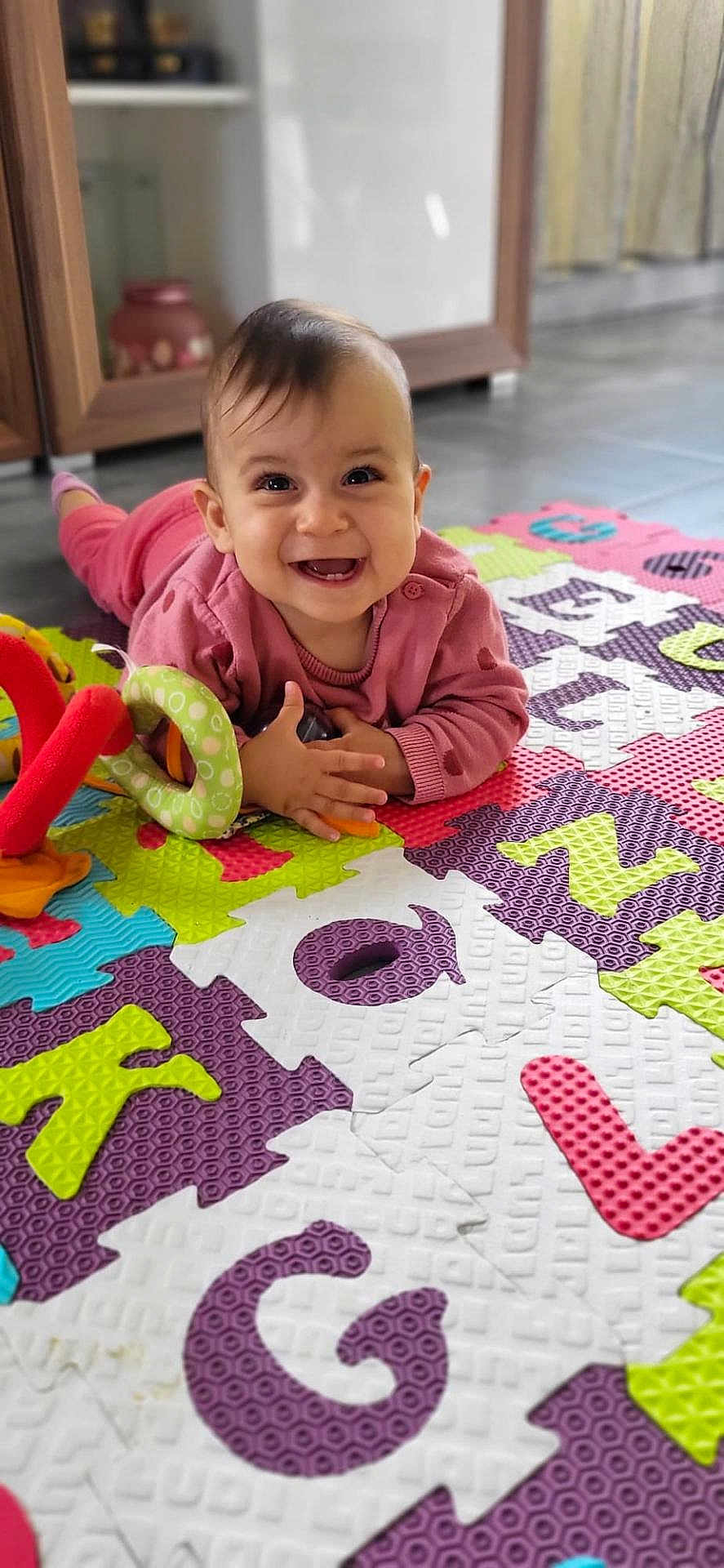 Nelly a rejoint le concours — aidez-le/la à gagner de superbes lots ! baby, child, smiling, toy, colorful_mat, indoor, floor, play, pink_clothing, happy, portrait, face, hands, head, infant, cute, home, puzzle_mat, early_learning, toddler