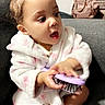 Kayla Ii is registered to the contest to win money with this photo: baby, toddler, child, hairbrush, robe, pink, white, couch, indoor, expression, face, person, seated, backpack, furniture, cute, happy, childhood, home, play
