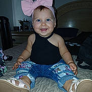 Alysha is registered to the contest to win money with this photo: baby, child, smiling, blue_eyes, pink_bow, headband, jeans, floral_pattern, shoes, bed, quilted_bedspread, indoor, portrait, happy, cute, fashion, sitting, person, infant, casual