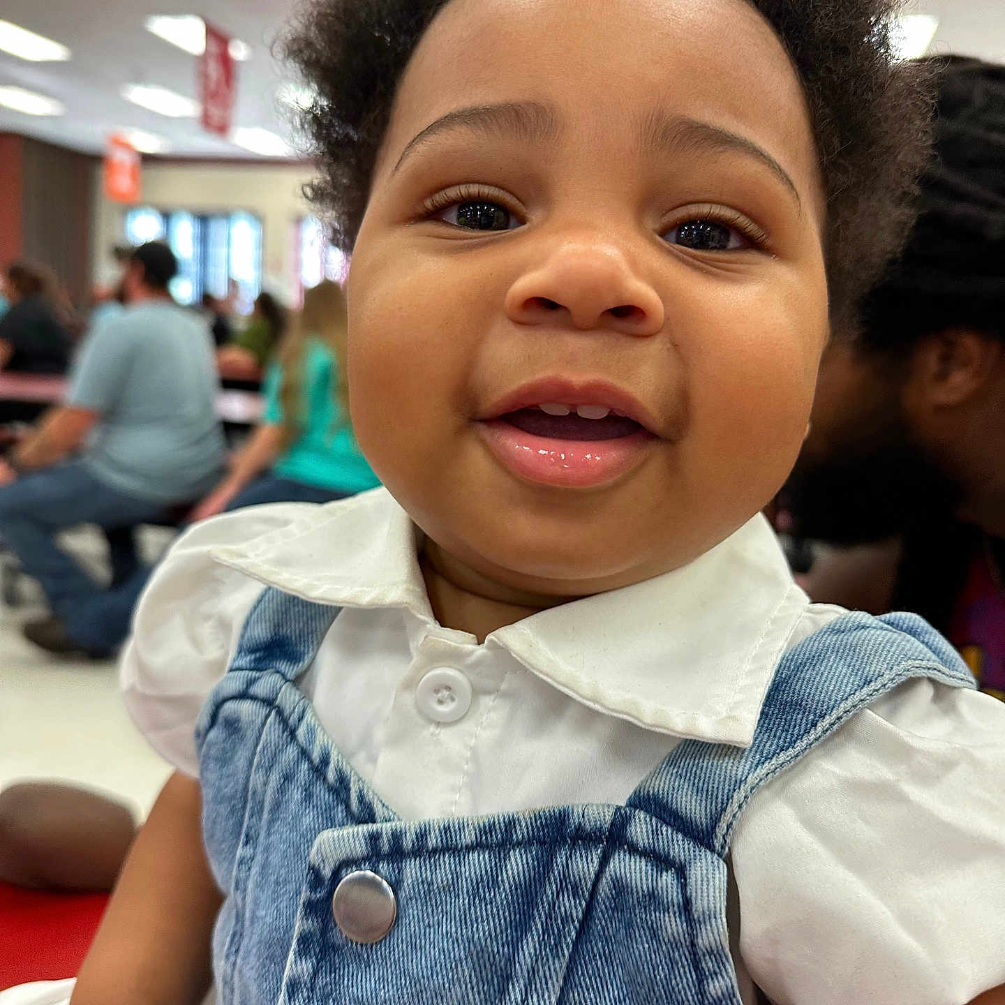 Millie Rain joined the competition — help win amazing prizes! baby, child, smiling, denim_overalls, white_shirt, blue_bow, curly_hair, indoor, people, background, close_up, portrait, cute, happy, infant, fashion, casual_clothing, person, face, expression