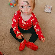 Payton is registered to the contest to win money with this photo: toddler, child, face_paint, red_shoes, red_shirt, carpet, toy, book, plaid_blanket, indoor, sitting, cute, portrait, playful, freckled_face, blue_eyes, casual_clothing, floor, young_child, looking_up