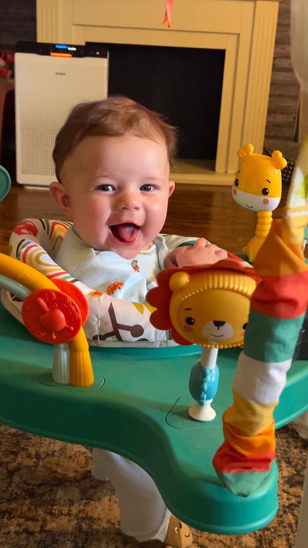 Zander is registered to the contest to win money with this photo: baby, child, smiling, happy, indoor, toys, activity_center, colorful, face, cute, infant, play, furniture, floor, clothing, person, home, bright, joyful, seat