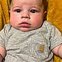 Zander is registered to the contest to win money with this photo: baby, infant, child, face, eyes, expression, clothing, shirt, pocket, logo, blanket, yellow, soft, skin, hair, cute, portrait, indoor, closeup, person