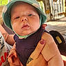 adult_hand, baby, child, closeup, clothing, expressionless, face, hand, hat, holding, infant, nail_polish, outdoor, person, porch, skin, sleeveless, sunlight, tattoo, wood