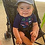 baby, black_stroller, cap, child, colorful_clothing, drool, footwear, hands, happy, infant, legs, outdoor, person, playful, seat, seatbelt, smiling, stroller, summer, sunlight